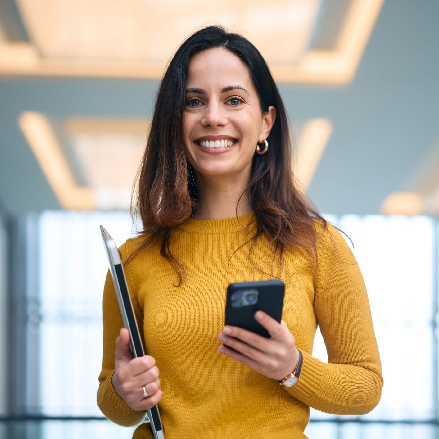 Frau in Gelb mit Smartphone in der Hand