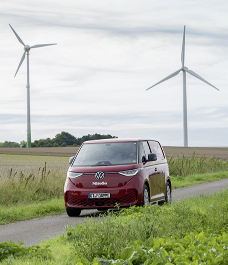 Ein roter Bulli mit Miele Logo auf einem Feldweg