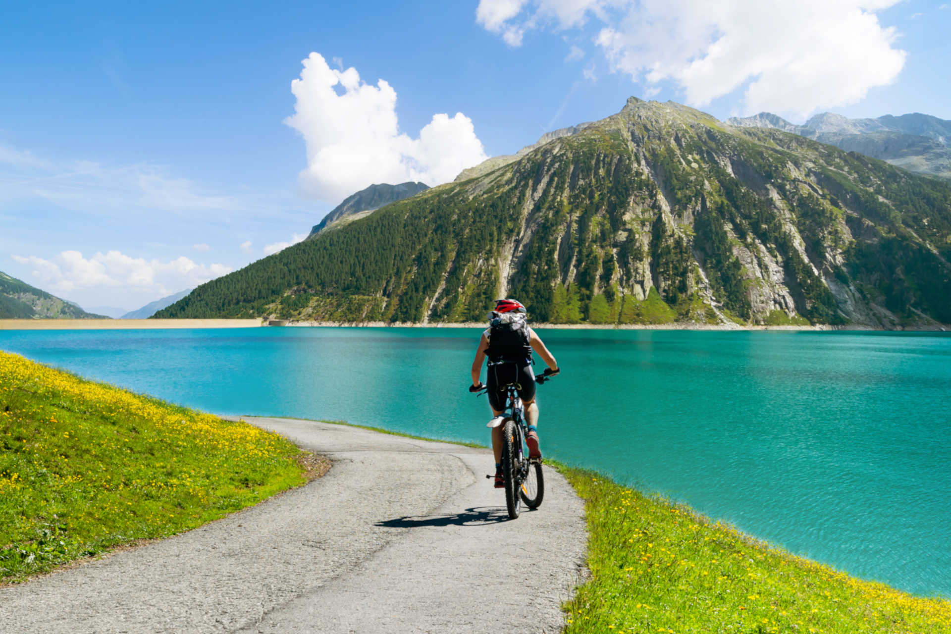 Für eine wunderschöne Fahrradtour über die Alpen Eine Frau fährt an einem See entlang