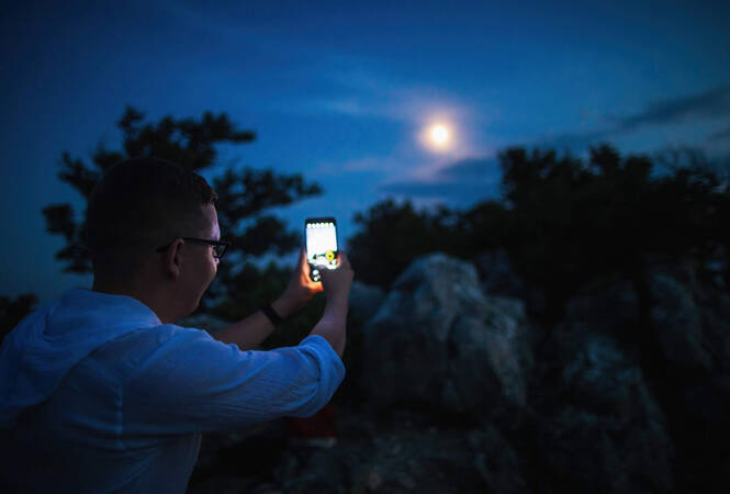 Mann fotografiert Mond mit Smartphone