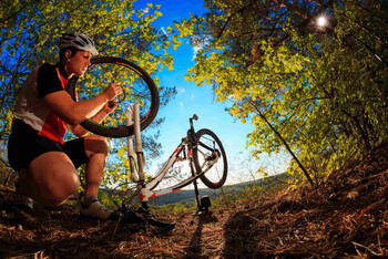 Mann repariert Fahrrad im Wald