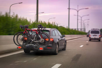 Auto fährt auf der Straße. Am Heck des Autos ist ein Fahrradträger befestigt.