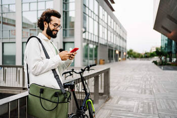 Mann steht neben Rad mit Handy in der Hand