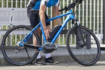 Mann hält die Hände an den Akku eines blauen E-Bikes