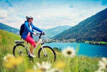 Eine Frau fährt auf einem E-Bike. Im Hintergrund befindet sich eine schöne Landschaft.
