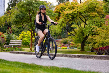 Frau auf Fahrrad fährt durch Park.