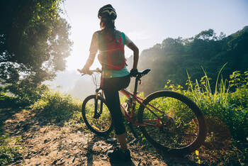 Person steht mit ihrem Mountainbike im Wald