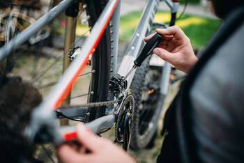 Mann schraubt an der Schaltung von einem Fahrrad.