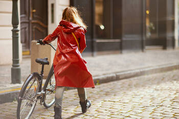 Frau in Regenjacke schiebt Fahrrad