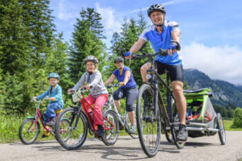 Familie fährt auf Fahrrädern Waldweg entlang