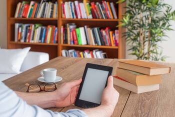 Kindle in gemütlicher Umgebung von zwei Händen gehalten