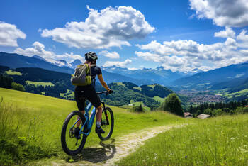 Frau auf E-Mountainbike fährt durch die Berge