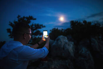 Mann fotografiert Mond mit Smartphone