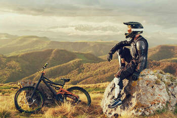 Ein Mountainbiker sitzt auf einem Fels