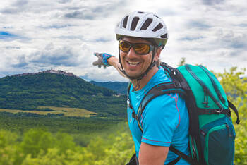 Mann fährt mit Fahrrad durch Slowenien und zeigt auf Landschaft