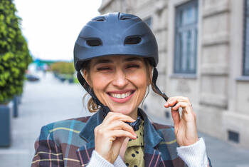 Eine lächelnde Frau schließt ihren Fahrradhelm