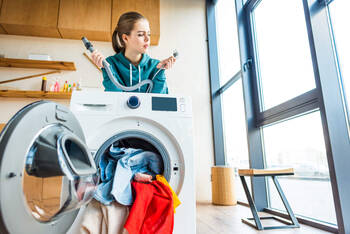 Frau steht verzweifelt hinter der Waschmaschine