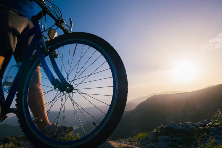 Berg- und Talfahrt – sicher auf die Berge Ein Fahrrad im Morgengrauen zwischen Bergen