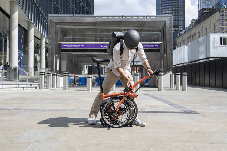 Person faltet das Brompton Faltrad