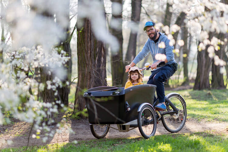 Ein Vater fährt mit seinem Kind Lastenrad