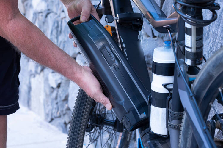 Mann tauscht Batterie seines E-Bikes