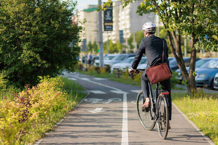 Mann auf Rad mit Helm fährt Fahrradweg entlang.