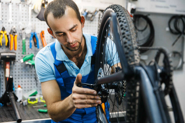 Mann führt Reparaturen an Fahrrad-Schaltung durch.