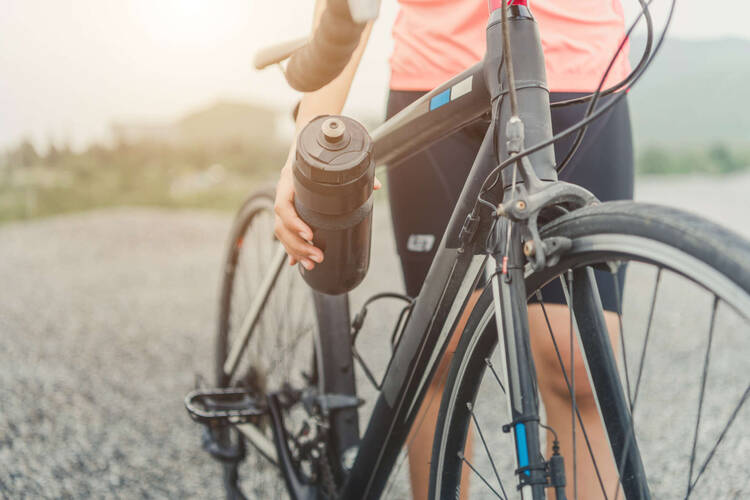 Eine Fahrradflasche wird am Fahrrad befestigt