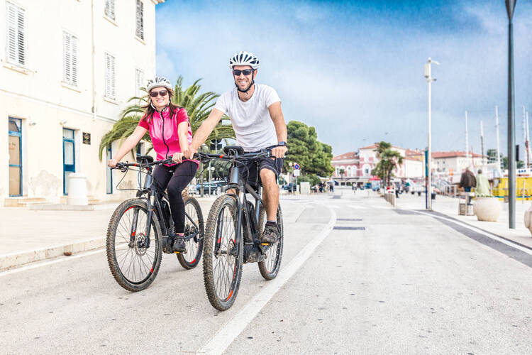 Zwei E-Bike Fahrer fahren glücklich die Straße entlang