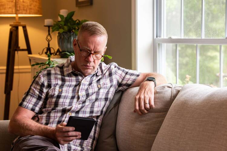 Mann sitzt auf Sofa und liest Kindle