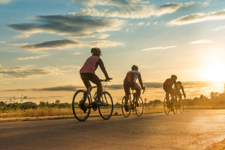 Vier Fahrradfahrer fahren dem Sonnenaufgang entgegen