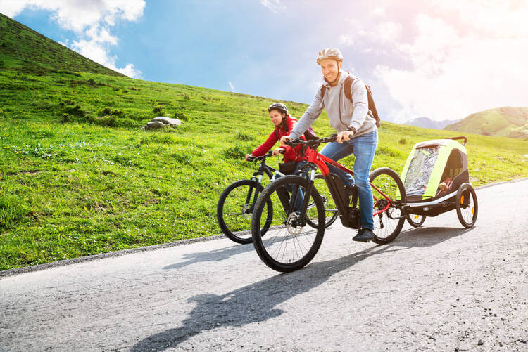 Ein Familie fährt mit ihren E-Bikes einen weg herunter