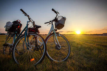 Zwei Fahrräder stehen im Vordergrund. Im Hintergrund ist ein Sonnenuntergang