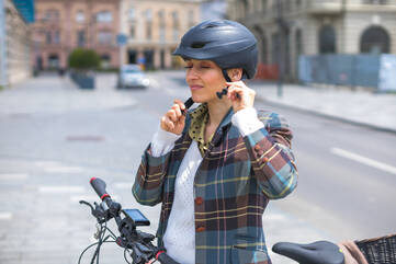 Eine Frau schließt auf ihrem Bike ihren Helm