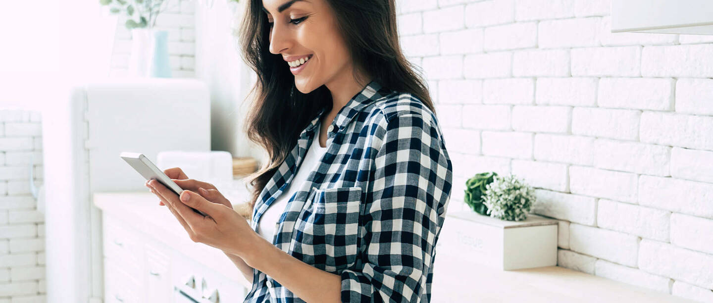 Frau mit Smartphone in der Küche