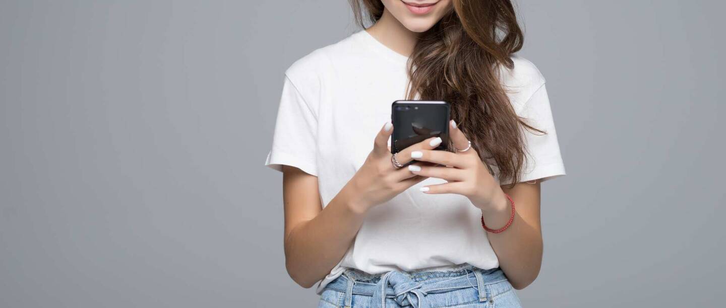 Ein Mädchen schaut lächelnd auf ihr Smartphone