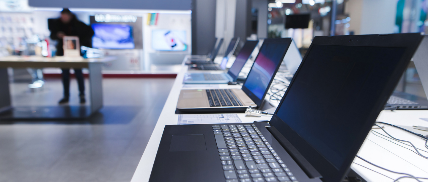 Mehrere Laptops stehen aufgereiht auf einem langen Tresen in einem Elektronikgeschäft.
