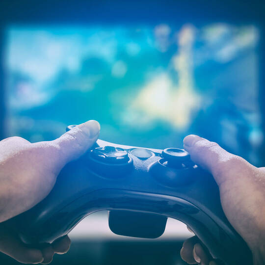 Zwei Hände die auf einem Controller zocken