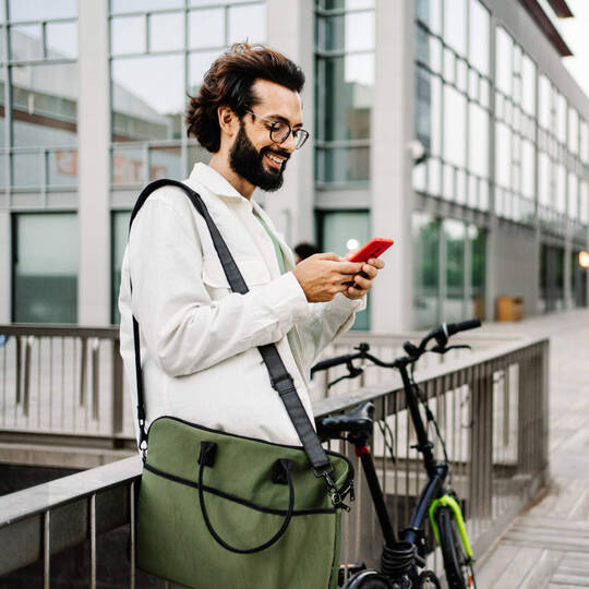 Mann steht neben Rad mit Handy in der Hand