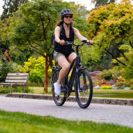 Frau auf Fahrrad fährt durch Park.