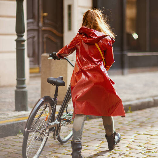 Frau in Regenjacke schiebt Fahrrad