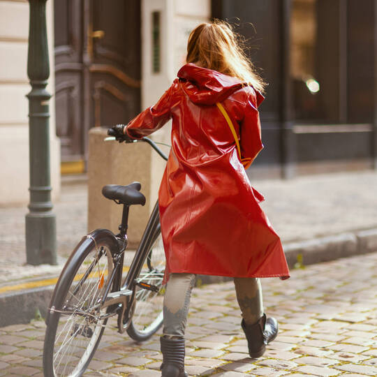 Frau in Regenjacke schiebt Fahrrad