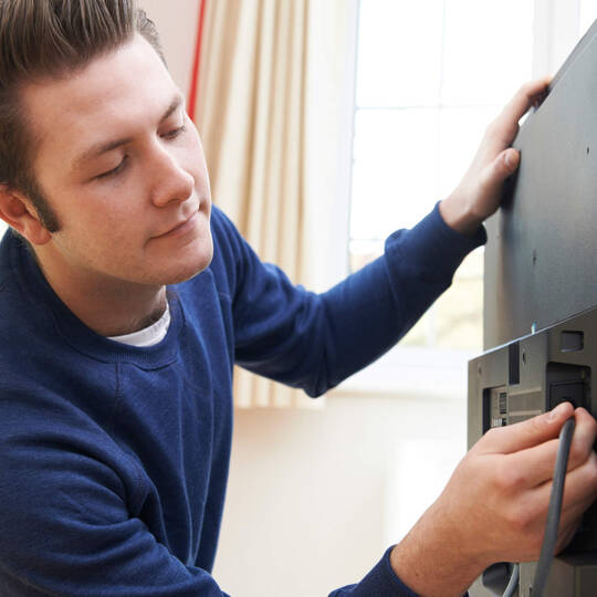 Mann steckt Kabel in Fernseher