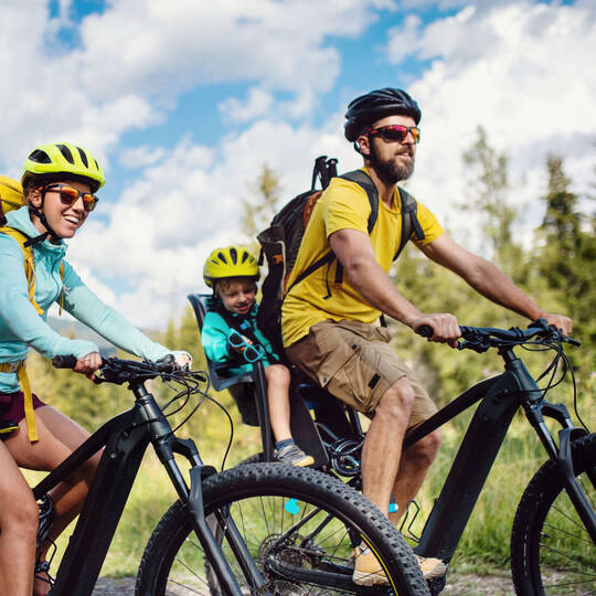Eine Familie fährt E-Bike mit Kind im Kinderfahrradsitz