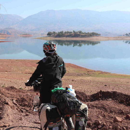 Frau fährt mit Fahrrad durch Landschaft in Marokko.
