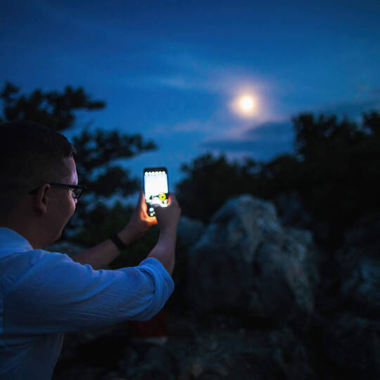 Mann fotografiert Mond mit Smartphone