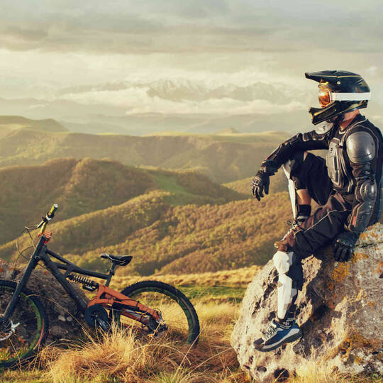 Ein Mountainbiker sitzt auf einem Fels