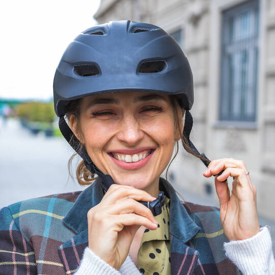 Eine lächelnde Frau schließt ihren Fahrradhelm