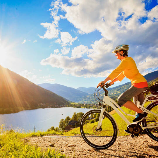 Eine Frau fährt mit dem Fahrrad vor einem See entlang