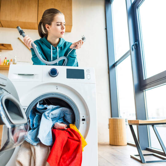 Frau steht verzweifelt hinter der Waschmaschine